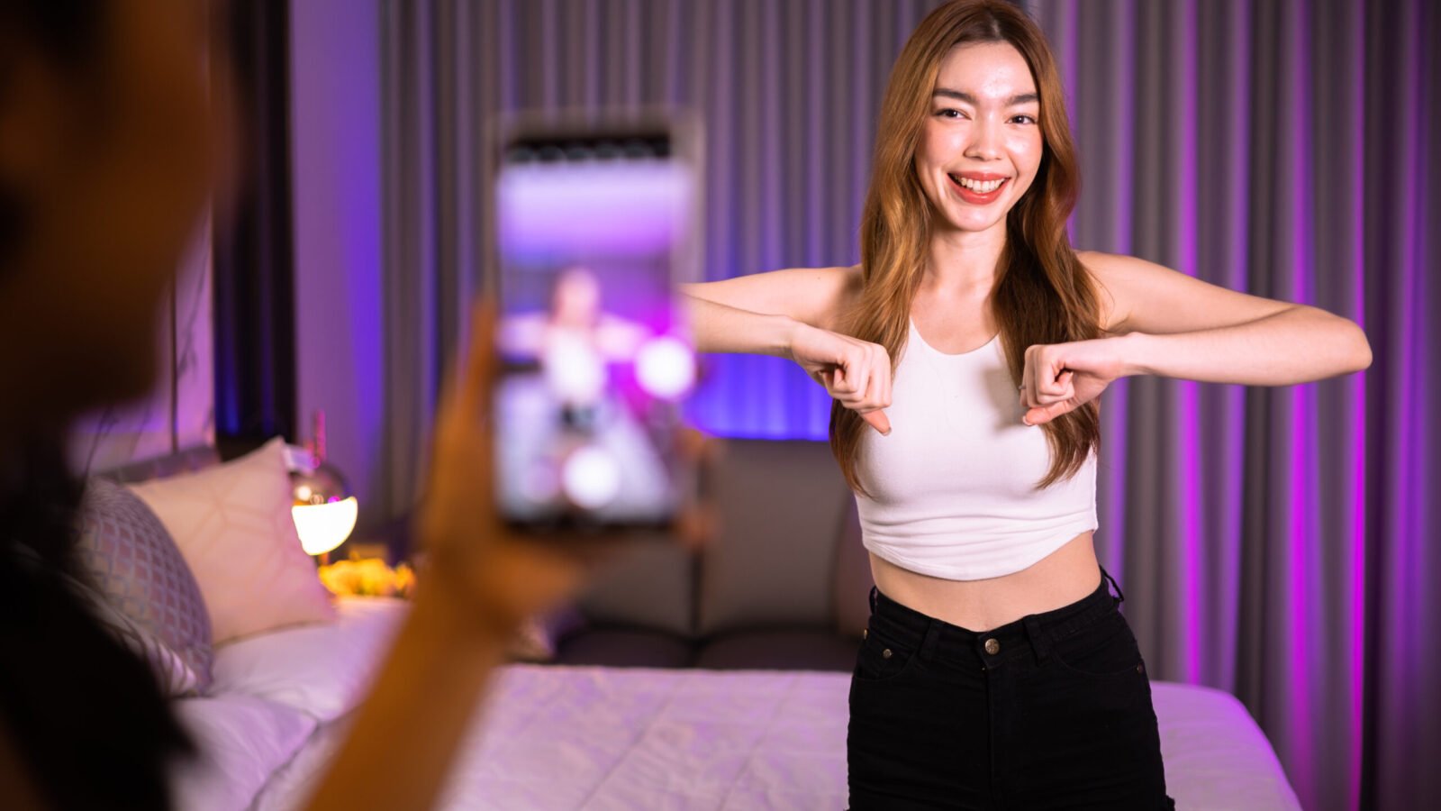 Asian and mixed race female influencer shooting dance video for Asian and mixed race female influencer shooting dance video for social media on mobile phone, having fun at home. To share video to social media application..