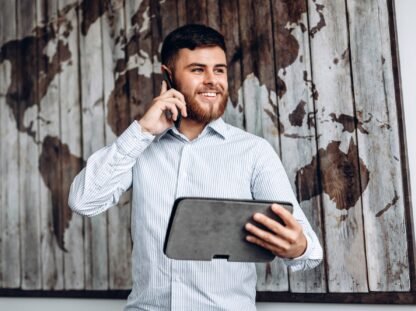 Handsome busy businessman talking on the phone and looking at important document on tablet.