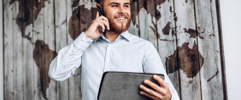 Handsome busy businessman talking on the phone and looking at important document on tablet.