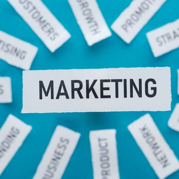 selective focus of word marketing and components related to marketing on pieces of paper on blue